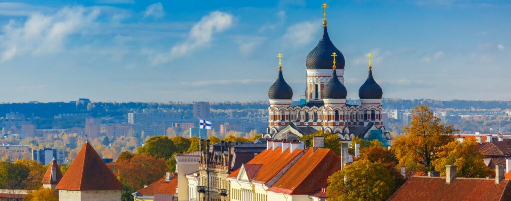 Panorama Tallinna z cerkwią Aleksandra Newskiego w tle, otoczoną złotymi jesiennymi drzewami i malowniczymi dachami.