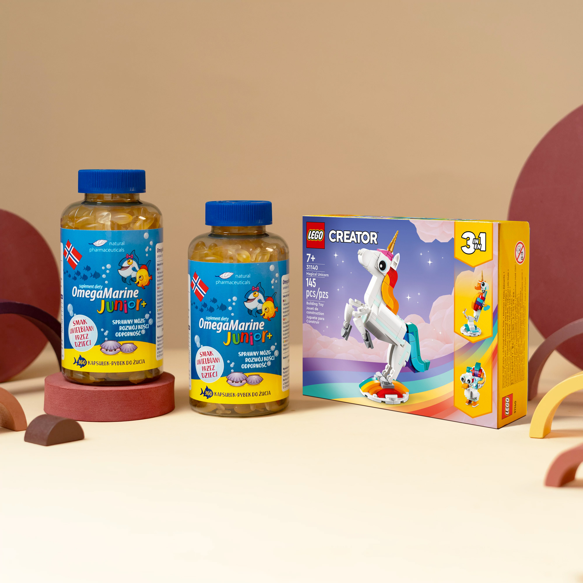 Obraz przedstawia suplementy diety OmegaMarine Junior oraz zestaw LEGO Creator 3 w 1 z kolorowym jednorożcem, idealny dla dzieci.