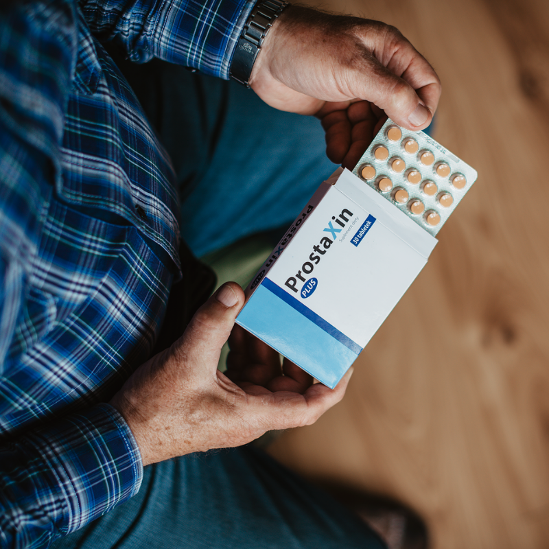 Mężczyzna trzyma opakowanie suplementu diety ProstaXin, wspomagającego zdrowie prostaty.