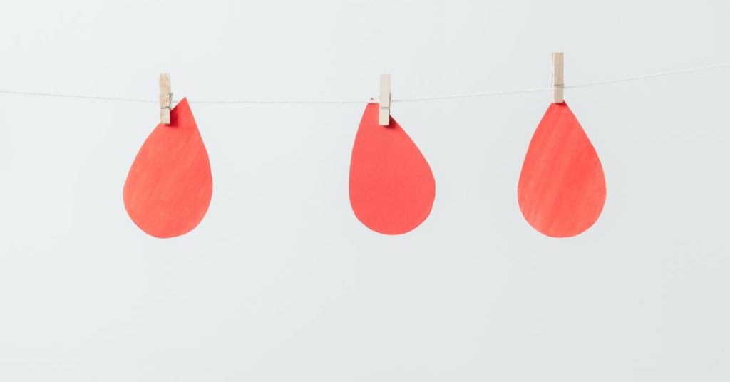 Kolorowe, czerwone krople zawieszone na sznurku w minimalistycznym wnętrzu, doskonałe jako element dekoracyjny lub inspiracja do rękodzieła.
