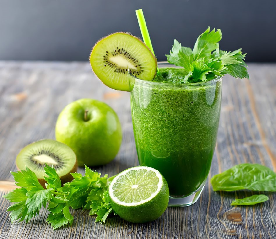 Szklanka zdrowego zielonego smoothie z kiwi, jabłkiem, selerem i limonką, otoczona świeżymi składnikami.