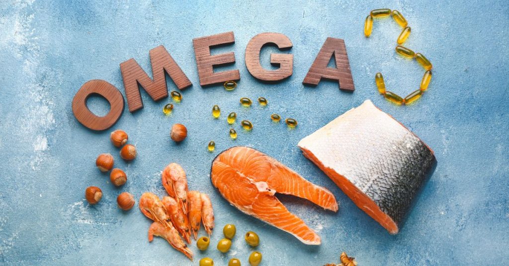 Obraz przedstawia różnorodne źródła kwasów omega-3, w tym ryby, krewetki oraz suplementy, układając je w atrakcyjny sposób na niebieskim tle.