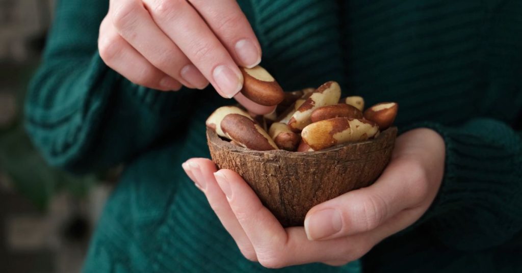 Kobieta trzyma w dłoniach miskę z orzechami brazylijskimi, podkreślając ich zdrowe właściwości i naturalny smak.